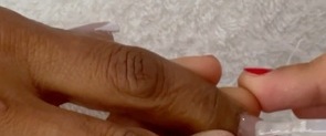 Esmalte aplicándose sobre las uñas de una clienta